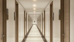 En lång, smal hotellkorridor med dörrar på båda sidor, som leder till enskilda rum.