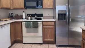 A kitchen with wooden cabinets, a stainless steel refrigerator, a microwave, an oven, and a water dispenser. - Stylish Tucson Getaway • Pool • Hot Tub • Game Zone - Sleeps 7 (Oro Valley)