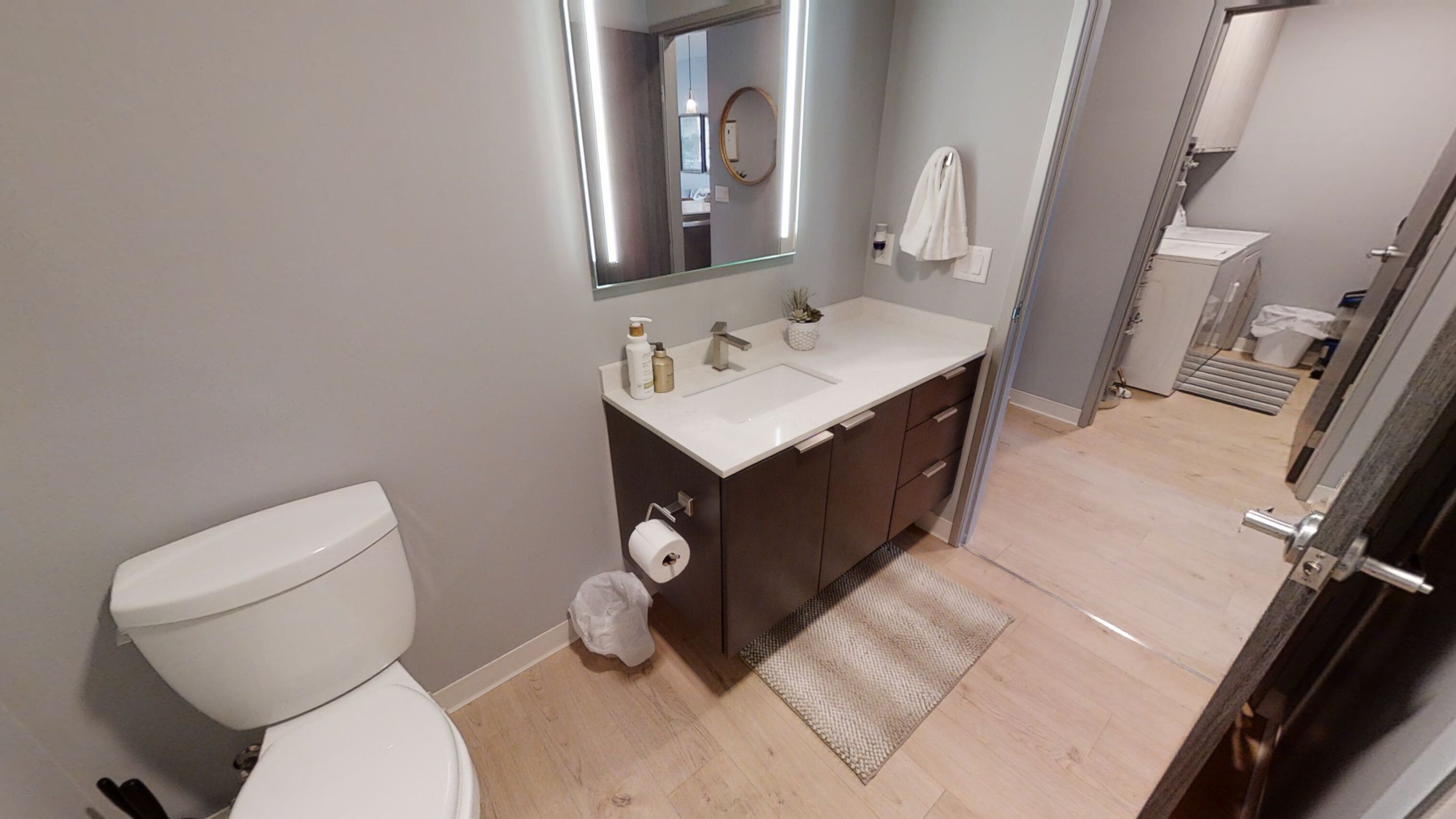 A modern bathroom with a toilet, sink, and mirror.