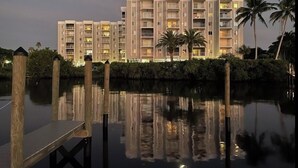 Un hotel de varios pisos con balcones, un muelle y palmeras.