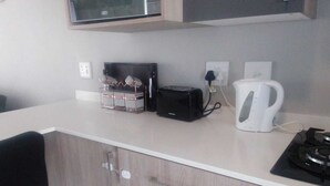 A compact kitchenette with a microwave, toaster, kettle, and stove. - Wonderful apartment in peaceful Midrand perfect for your stay (Midrand)