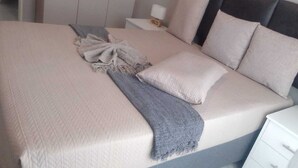 A neatly made bed with a grey throw blanket and pillows, a bedside table with a lamp, and a white nightstand. - Wonderful apartment in peaceful Midrand perfect for your stay (Midrand)