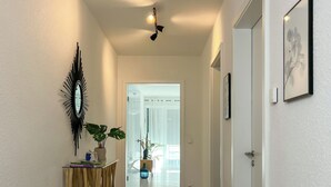 A hallway with a modern light fixture, a decorative mirror, and a small table with plants. - Experience Cochem: Moselle view, view of the Reichsburg & old town directly opposite (Cochem)