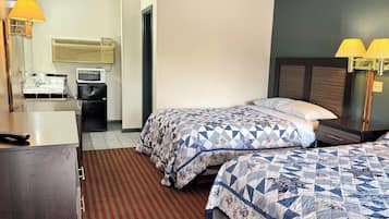 Habitación de hotel con dos camas, un escritorio, refrigerador, microondas y una lámpara.