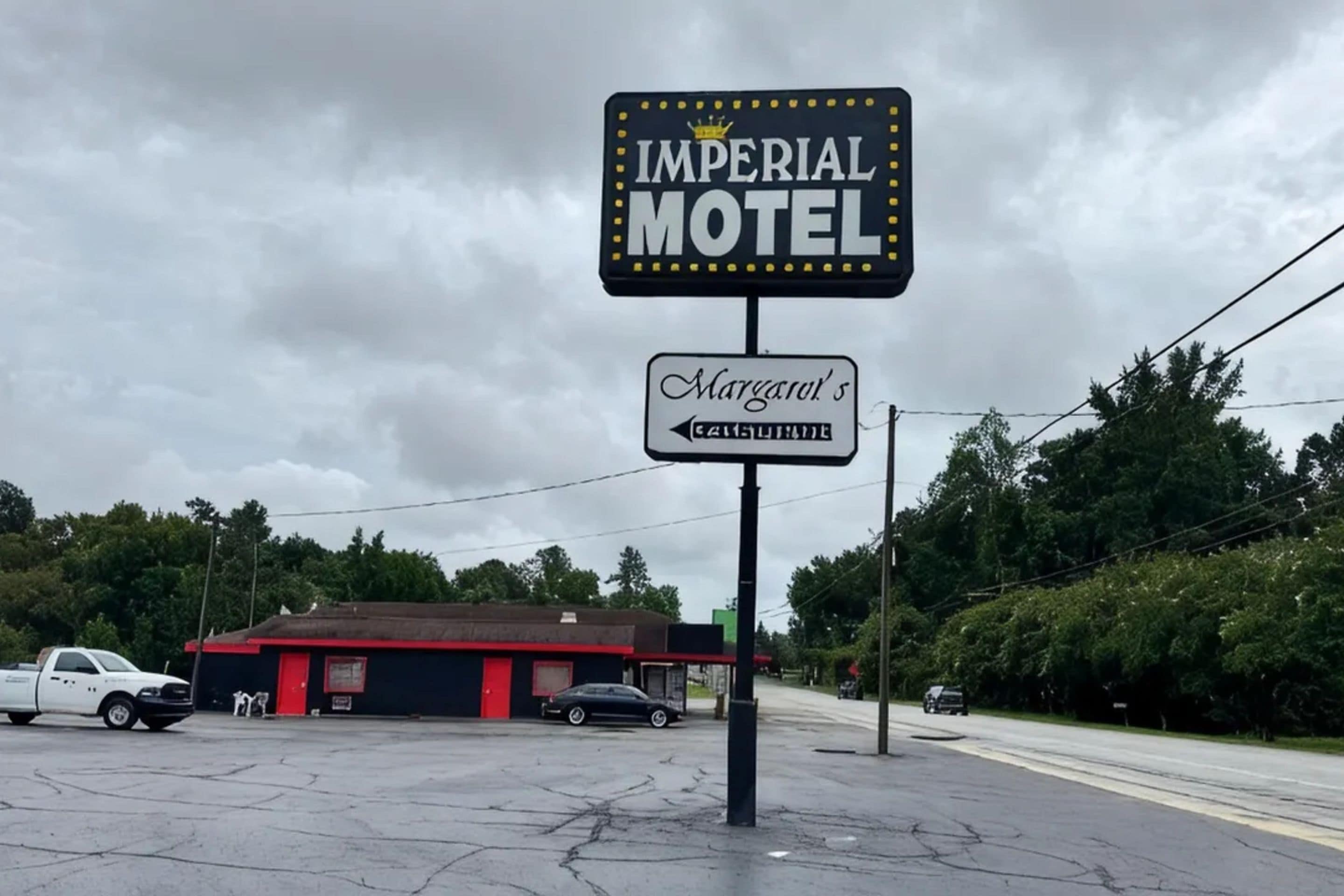 A motel sign with a name and a directional sign below it.
