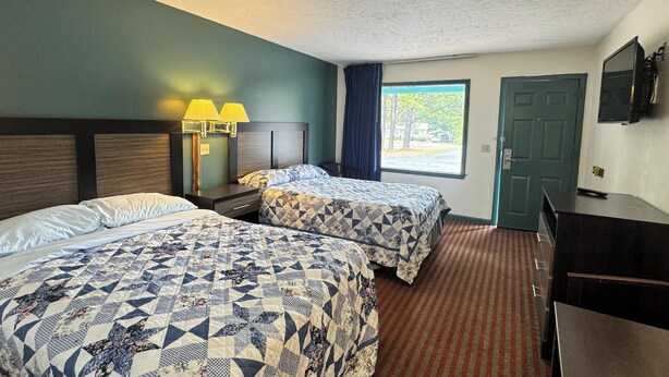 A hotel room with two beds, a desk, a TV, and a window with a view of trees. - Imperial Motel Near Marion HWY 76 (Mullins)