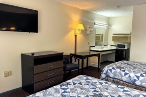 A hotel room with a flat-screen TV, a desk with a lamp, a small bathroom with a mirror, and two beds with patterned quilts. - Imperial Motel Mullins Near Marion Hwy 76 (Mullins)
