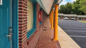 A hotel with a covered walkway, brick exterior, and a parking lot. - Imperial Motel Near Marion HWY 76 (Mullins)