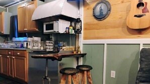 A kitchen with wooden cabinets, a microwave, a coffee maker, and a guitar on the wall.