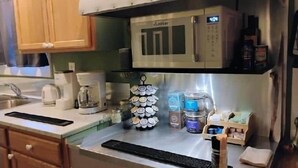 A kitchen with a microwave, coffee maker, and a spice rack.