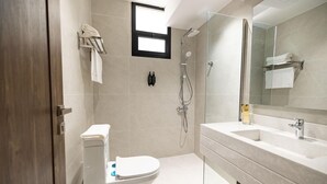 A modern bathroom with a toilet, shower, and sink. - Royal Edition Hotel Apartments (Buraydah)