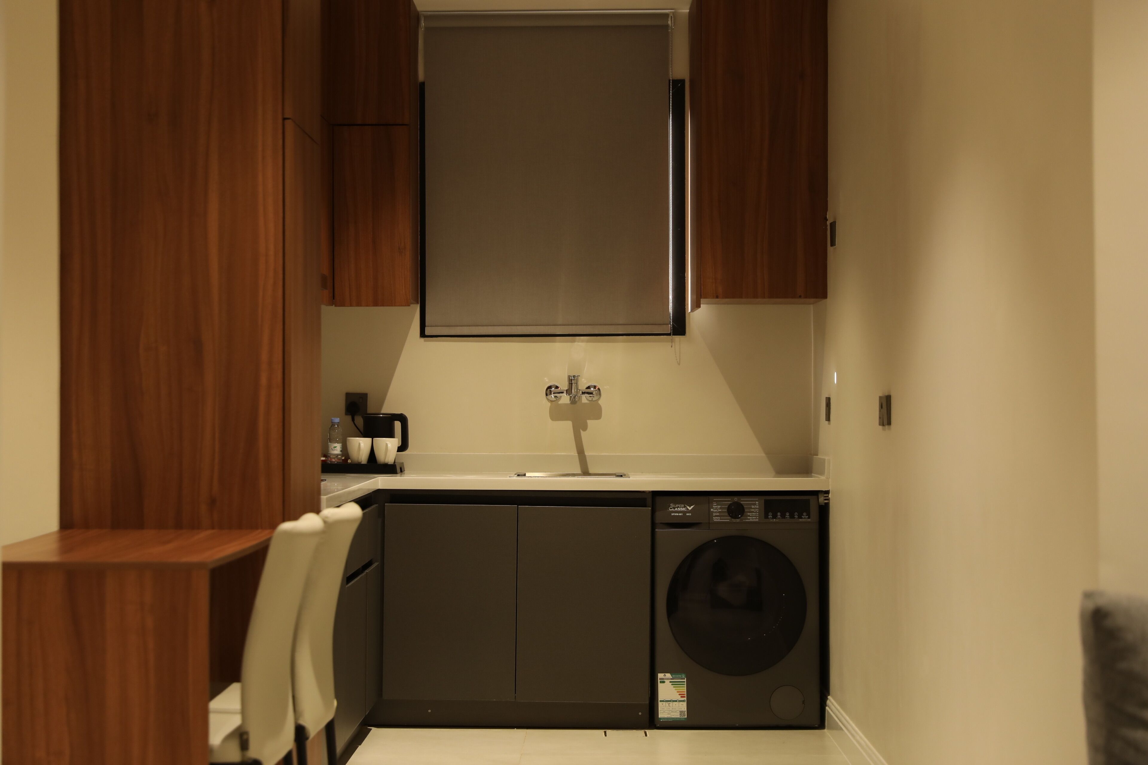 Een kleine wasruimte met een wasmachine, een wasbak en houten kastjes.