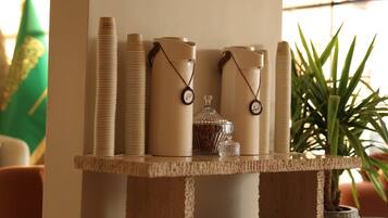 A table with stacked items, a glass container, and a potted plant.
