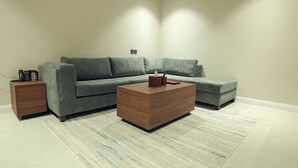 A modern living room with a grey sofa, a wooden coffee table, and a patterned rug. - Royal Edition Hotel Apartments (Buraydah)