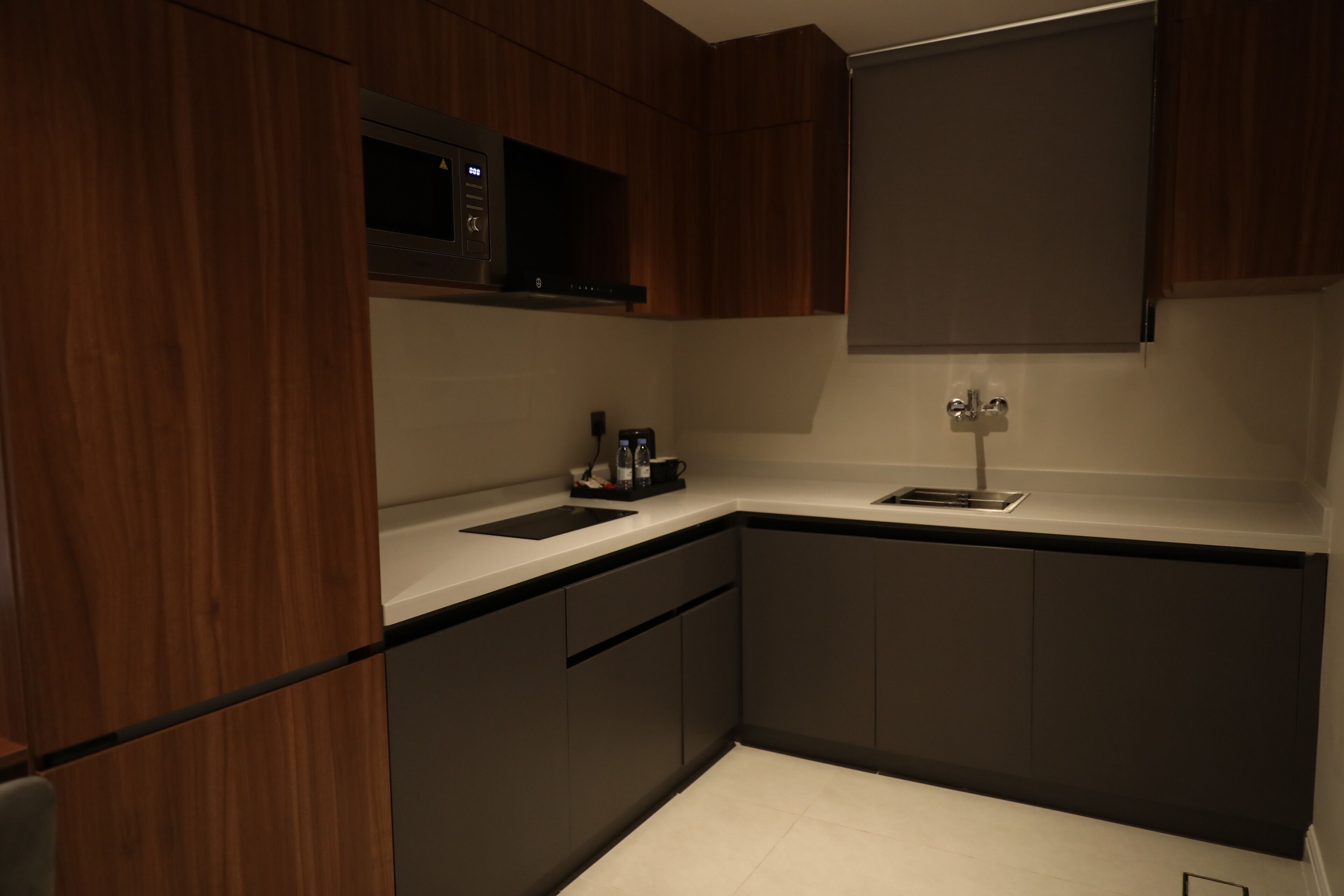 A modern kitchen with dark wood cabinets, a white countertop, and a built-in microwave.
