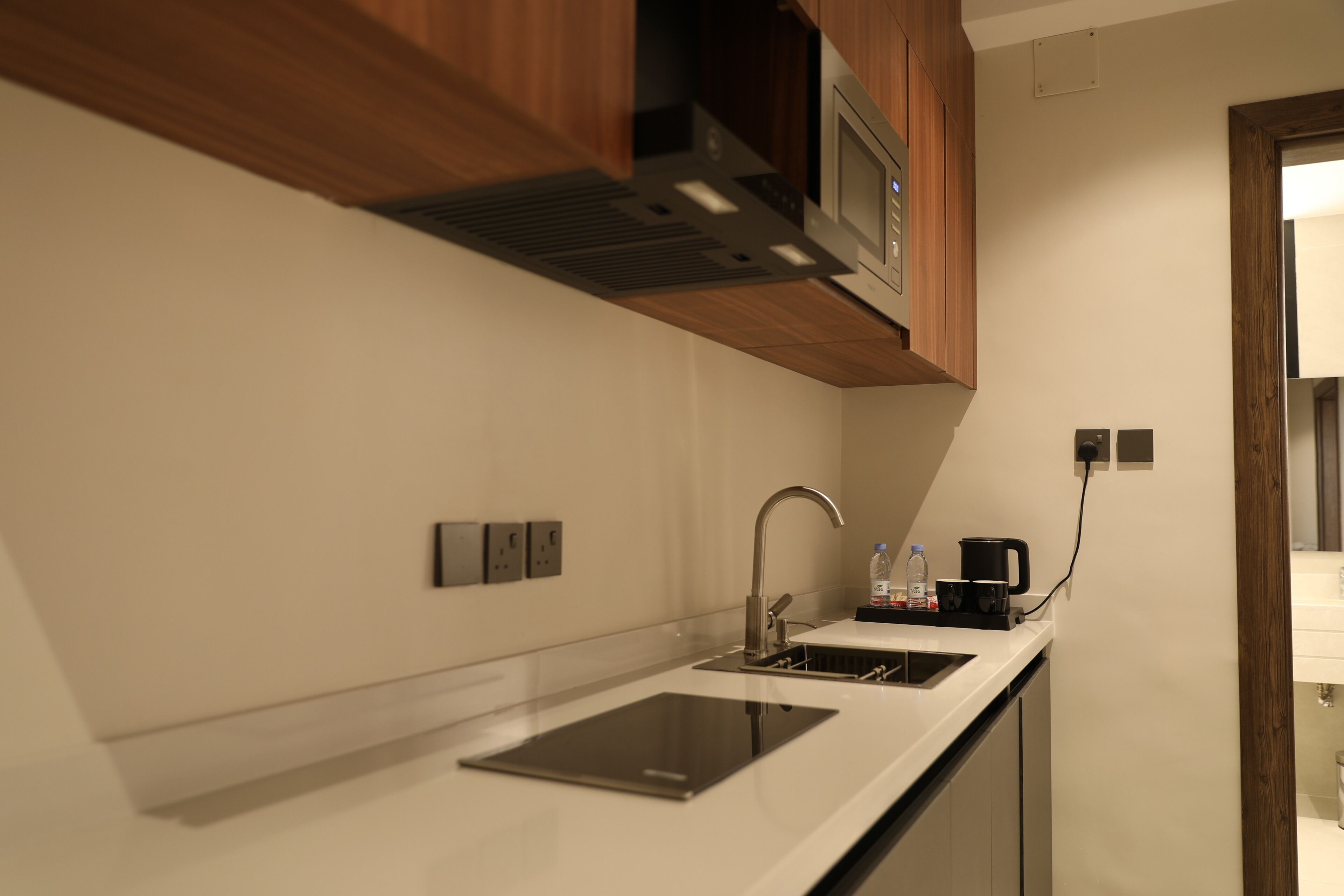A modern kitchen with a built-in microwave, a stainless steel sink, and a coffee maker.