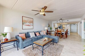 A spacious living room with a grey sectional sofa, a coffee table, and a ceiling fan. - 2BR w/ View & Resort Perks: Suntide III - Unit 907 (South Padre Island)