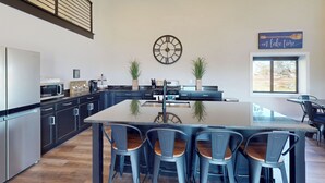 Una cocina moderna con una isla central, taburetes de bar y un reloj en la pared.