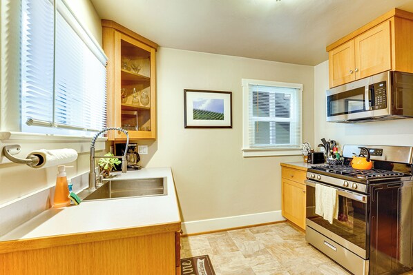 A kitchen with wooden cabinets, a stainless steel stove, a microwave, and a sink with a towel holder. - Steps to Sand: 'Beach Hill Bungalow' w/ Patio (Santa Cruz)