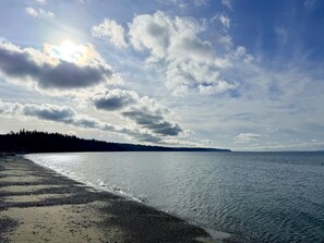 A beach with a calm sea, a clear sky, and a distant tree line. - Restorative Island Retreat - Beach Access and Private Half-Acre (Coupeville)