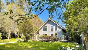 Une maison avec un toit en pente, un porche à l’avant et une pelouse bien entretenue.