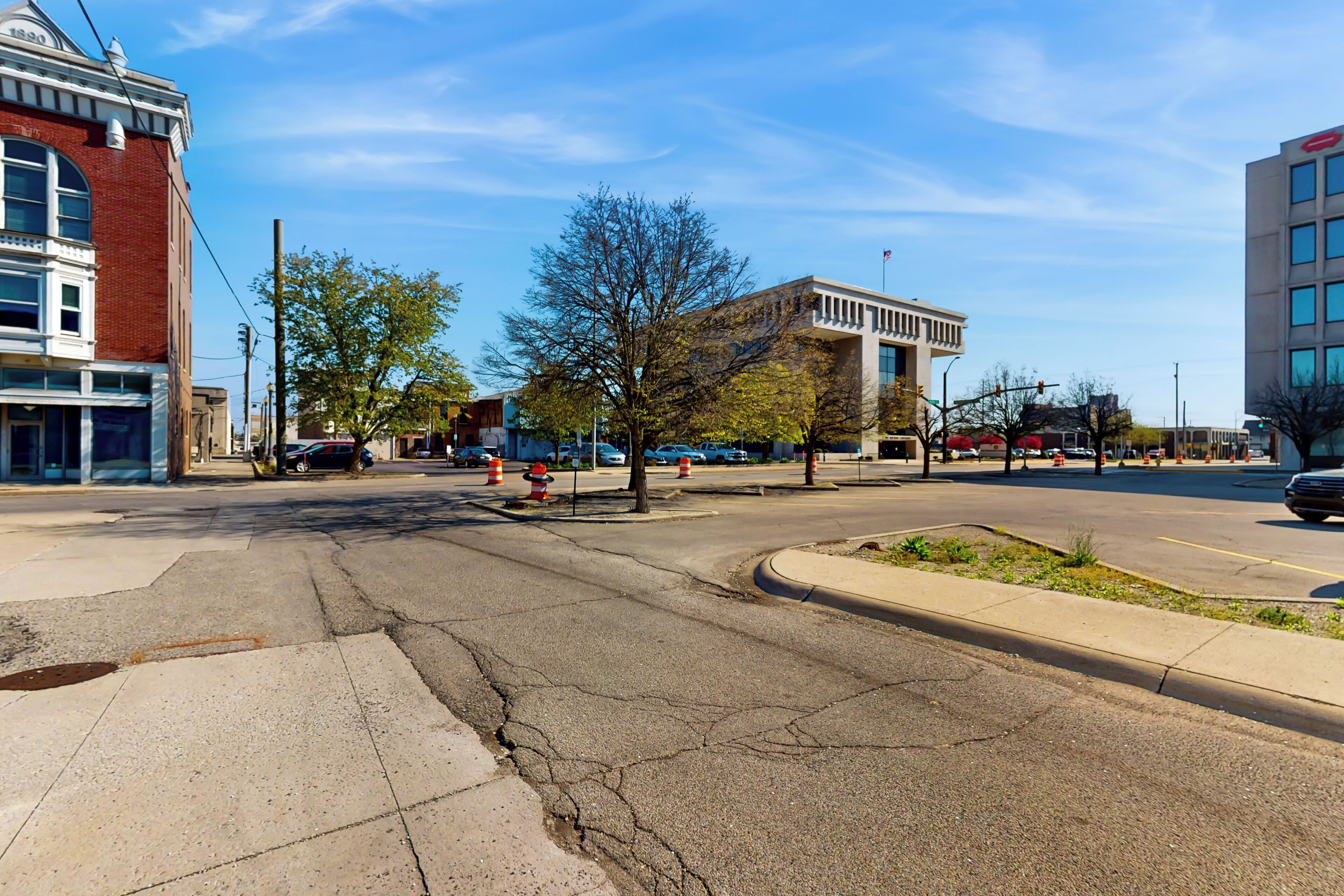 A street view with a mix of modern and older buildings, a clear sky, and a pedestrian crossing.