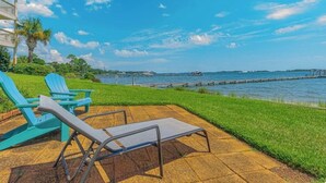 A patio with lounge chairs, a grassy area, and a view of the water. - 🌴 Waterfront-Beach-Swimming-Fishing-Dock-Double sized private Balcony (Mary Esther)