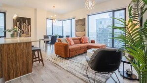 A modern living room with a large window, a sofa, a dining area, and a kitchen island. - Free Indoor Parking Old Montreal 4 (Montréal)