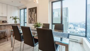 A modern dining area with a glass table, black chairs, and a city view through large windows. - Free Indoor Parking Old Montreal 4 (Montréal)