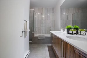 Ein modernes Badezimmer mit großem Spiegel, zwei Waschbecken und einer Duschkabine.