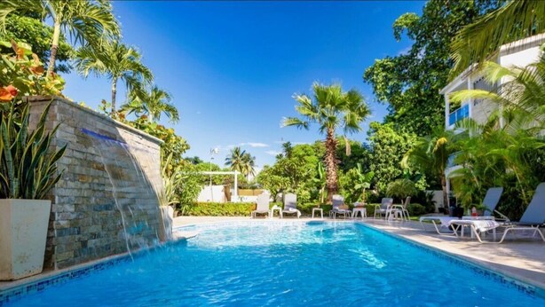A swimming pool with lounge chairs and palm trees. - Stylish 2BR in Sosua with Pool, Bbq, Fast Internet & Back up Generator (Sosúa)