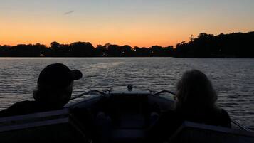 Two people on a boat with a view of a sunset over water.