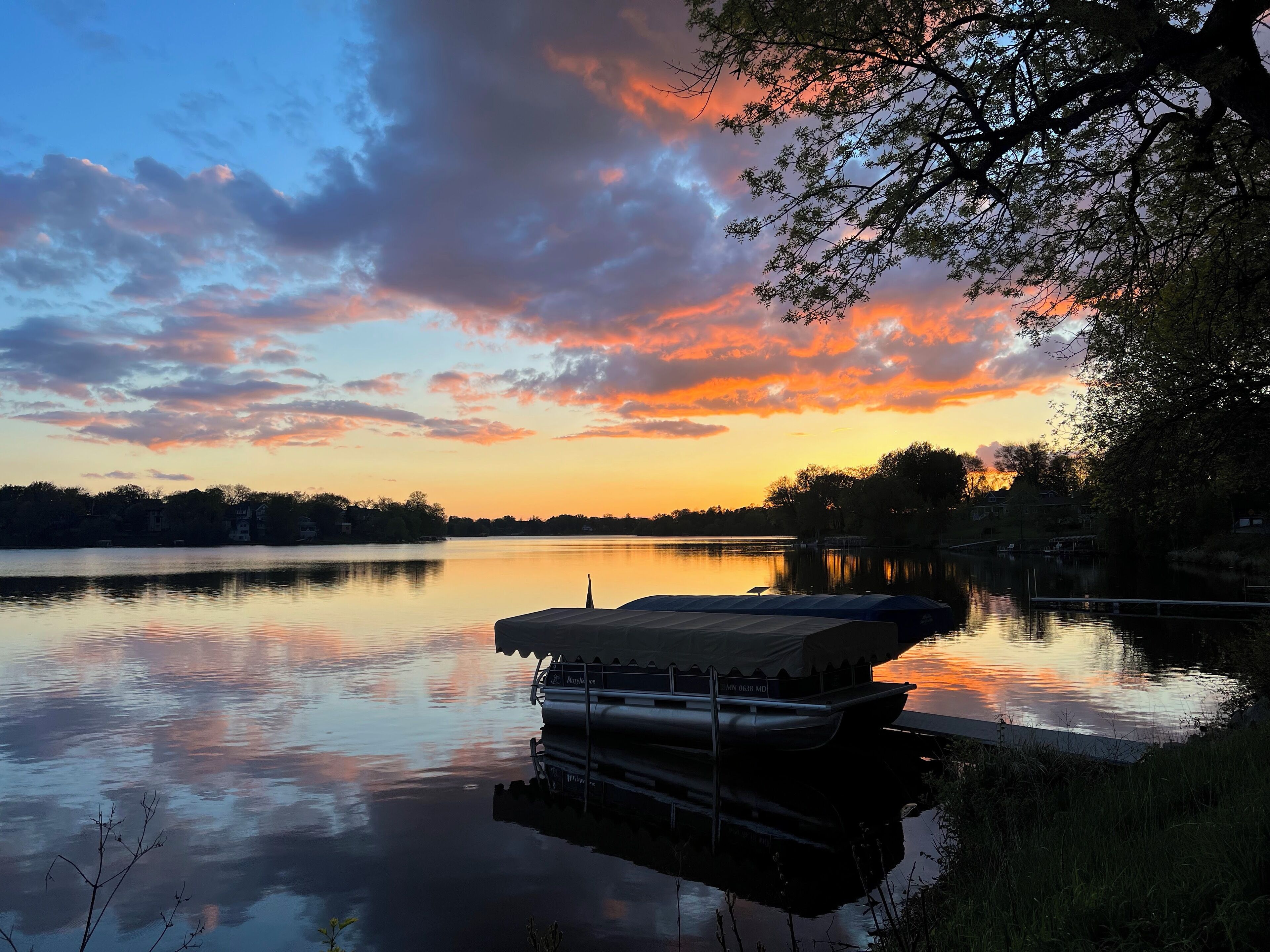 A calm lake at sunset with a docked boat.