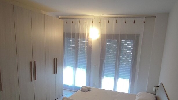 A bedroom with a bed, a wardrobe, and a window with blinds. - Holiday House iolo (Prato)