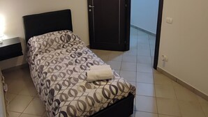 A bedroom with a bed, a nightstand, a door, and a light fixture on the ceiling. - Holiday House iolo (Prato)