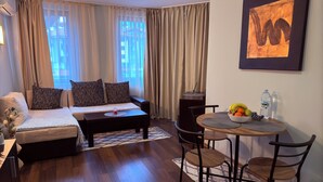 Ein modernes Hotelzimmer mit einer Couch, einem Esstisch mit Stühlen, einem kleinen Couchtisch und einem Bild an der Wand.