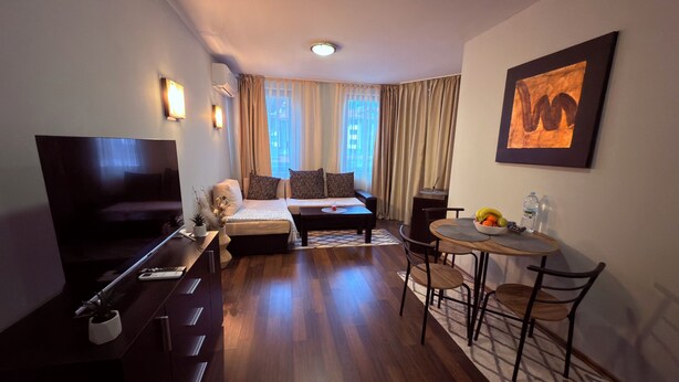 Ein gemütliches Hotelzimmer mit Schlafsofa, einem kleinen Esstisch, einem Fernseher und einem Bild an der Wand.