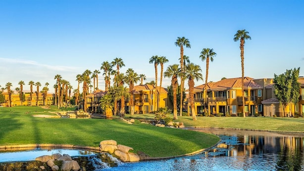 A golf course with a pond, palm trees, and a clubhouse with multiple buildings. - JW Marriott's Desert Springs Villas I - Access to Marriott Spa, Sleeps 6-8 (Palm Desert)