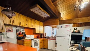 A kitchen with wooden cabinets, a microwave, a stove, and a refrigerator. - Large Family Home at Deka Lake (Lone Butte)