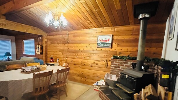 A cozy cabin interior with a dining area, wooden walls, a fireplace, and a guitar on the wall. - Large Family Home at Deka Lake (Lone Butte)