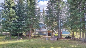 A residential property with a two-story house, a backyard with a picnic table, and a fire pit. - Large Family Home at Deka Lake (Lone Butte)