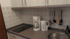 A kitchen with a stainless steel sink, a Bosch coffee maker, and various utensils hanging on the wall.
