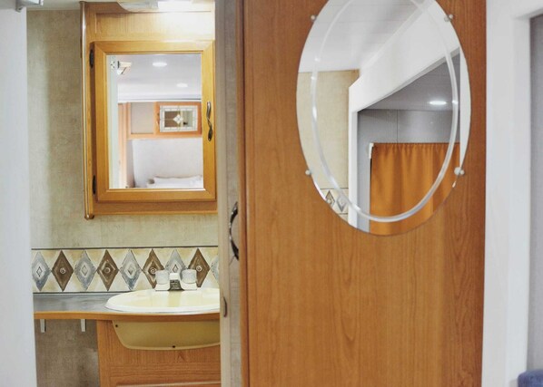 A bathroom with a wooden vanity, a mirror, and a tiled backsplash. - Tiny Soul  (Santa Teresa)