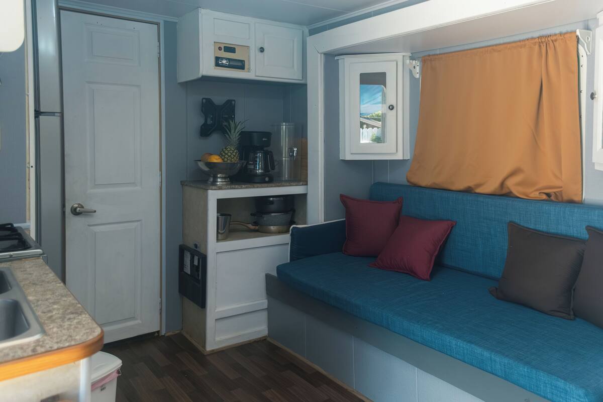 A compact kitchenette with a coffee maker, a bowl, and a pineapple on the counter.