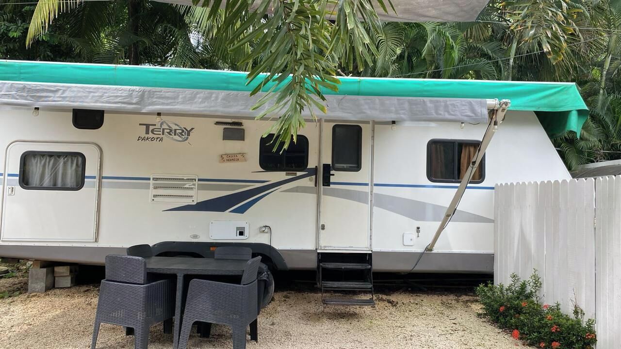 A Terry Dakota RV with a covered patio area, a small table, and two chairs.