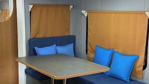Ett litet rum med ett bord och en bänk, en spegel och gardiner.