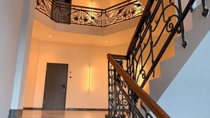 Un escalier orné de rampes en métal noir et d’une main courante en bois, menant à l’étage supérieur.