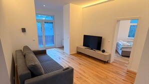 Un salon moderne avec un canapé gris, un téléviseur à écran plat et un plancher en bois.