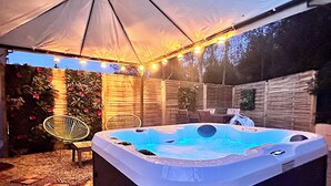 A hot tub under a tent with string lights, surrounded by a wooden fence and potted plants. - The birdies house (Trans-en-Provence)