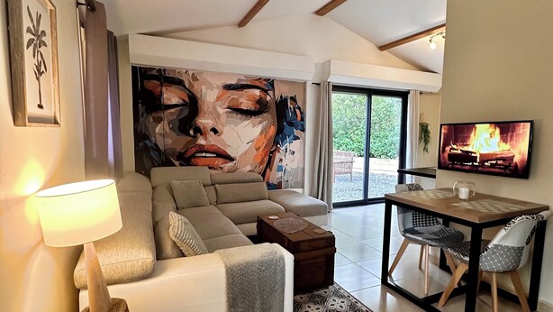 A modern living room with a large abstract painting, a sofa, a coffee table, a TV, and a dining area with chairs. - The birdies house (Trans-en-Provence)